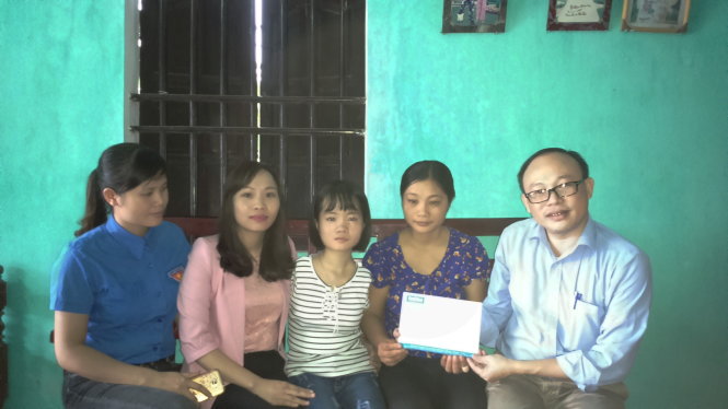 Đại diện báo Tuổi Trẻ trao tiền của bạn đọc cho gia đình em Lê Thị Thắm - Ảnh: H.ĐỒNG