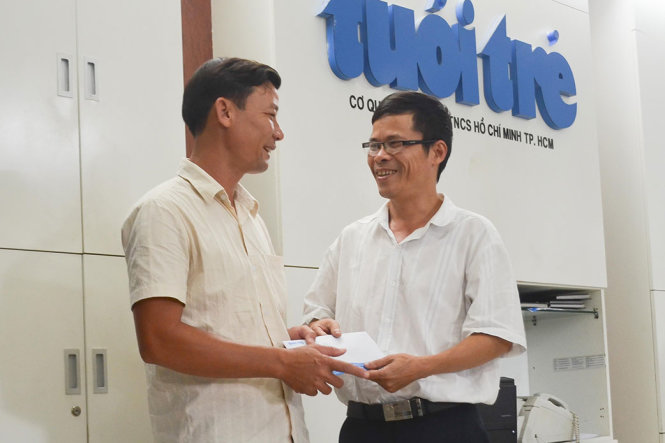 Đại diện báo Tuổi Trẻ (phải) trao quà cho anh Phạm Thọ - Ảnh: TẤN LỰC