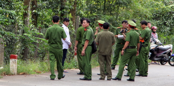 Nghi can Nhân (đội nón, áo trắng) được CA đưa đến hiện trường.
