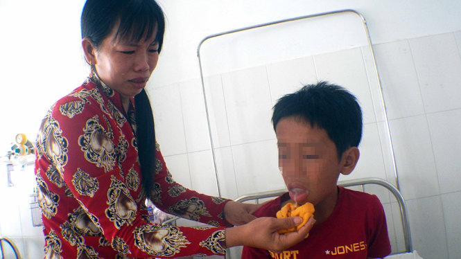 Cháu Thêm đang được chăm sóc và điều trị tại bệnh viện trong tình trạng miệng lưỡi bị sưng, chỉ có thể uống từng muỗng nước nhỏ - Ảnh: N.TRIỀU