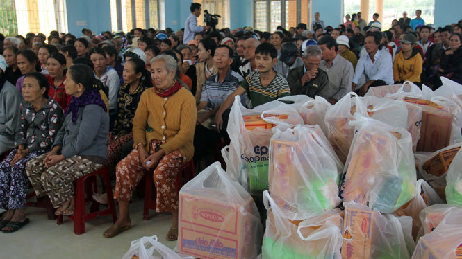 Người dân ngồi chật kín nhà cộng đồng xã Nghĩa Thương chờ những phần quà đầy yêu thương - Ảnh: Trần Mai