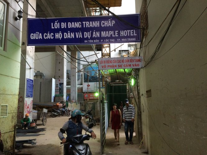 Người dân dựng rào sắt, ngăn lối đi chung của bốn hộ (bên phải) để yêu cầu doanh nghiệp trả tiền cao hơn - Ảnh: TR.TÂN