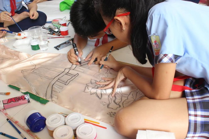 Các đội viên vẽ tranh trên áo dài - Ảnh: C.K.