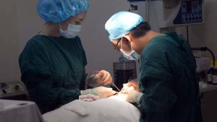 Bác sĩ mổ thẩm mỹ gương mặt cho một người dân Ảnh minh họa: HỮU KHOA