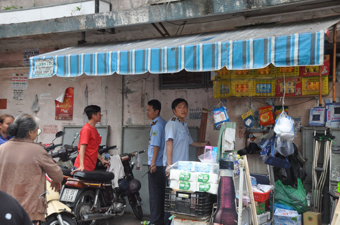 Nhân viên Đội Trật tự đô thị quận 5 dọn dẹp hàng hóa giúp người buôn bán trên vỉa hè trước BV Chấn thương chỉnh hình - Ảnh: NGỌC HÀ
