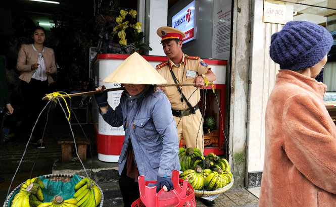 Anh Trương Hoài Phong, Đội Cảnh sát giao thông Công an TP. Đà Lạt, đỡ cho bà Tô Thị Nghĩa đưa gánh hàng rong đi - Ảnh: M.VINH