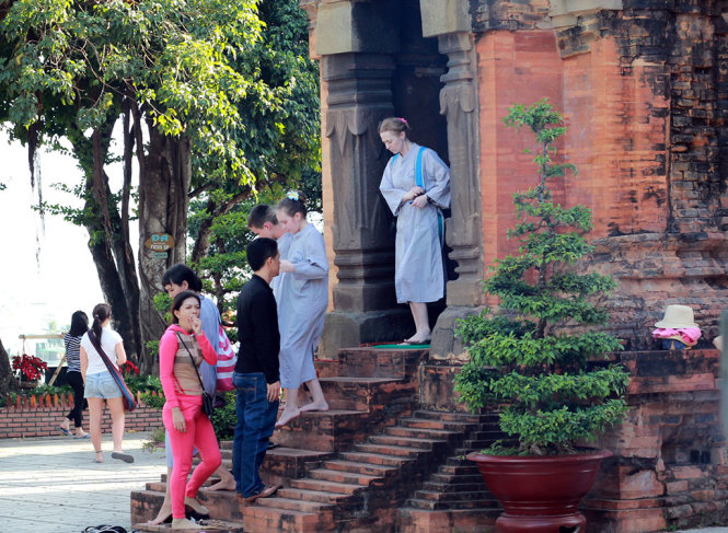 Nhiều du khách nước ngoài thích thú với bộ áo dài bằng vải lam khi đi tham quan tháp bà Ponagar - Ảnh: TR.TÂN