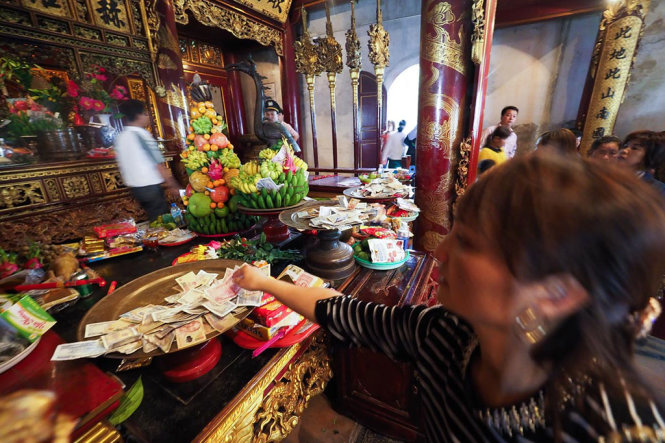 Một người phụ nữ đặt tiền lẻ tại Đền Thượng - Ảnh: NGUYỄN KHÁNH