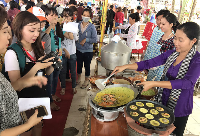 Khách tham quan nghệ nhân đổ bánh xèo - Ảnh: C.QUỐC
