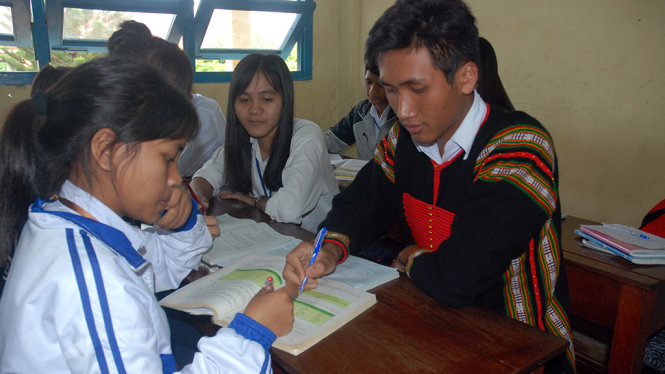 Dương Niê Quốc Phong đang trao đổi bài vở với các bạn học trong lớp - Ảnh: B.D.