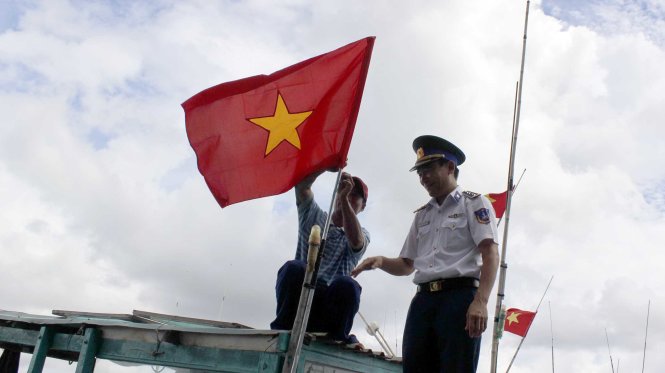 Cảnh sát biển thay lá cờ Tổ quốc mới cho tàu cá của ngư dân tại cảng Cát Lở sáng 10-5 - Ảnh: Đông Hà