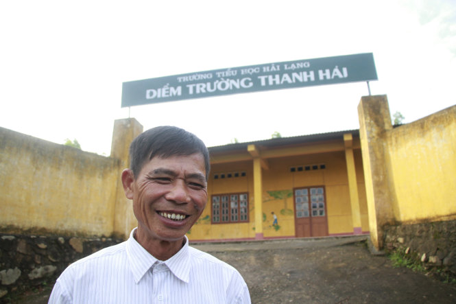 Thầy Ba “khùng” tươi cười bên điểm trường tiểu học được xây trên đất của gia đình mình - Ảnh: Đ.H.