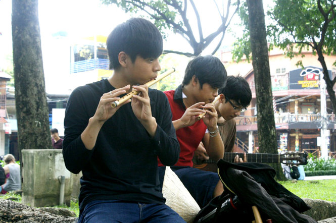Các bạn trẻ thổi sáo, chơi đàn guitar tại công viên - Ảnh: ĐỖ TRƯỜNG