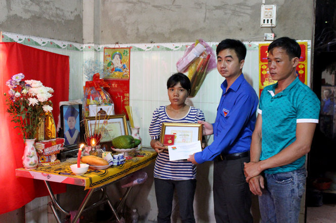 Anh Trần Quốc Duy - Bí thư Tỉnh Đoàn thay mặt Hội đồng đội Trung ương trao huy hiệu “ Tuổi trẻ dũng cảm” cho phụ huynh em Trần Đức Đông - Ảnh: B.L
