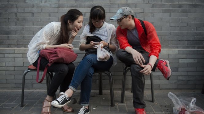 Một nhóm bạn trẻ Trung Quốc chăm chú nhìn vào điện thoại thông minh.