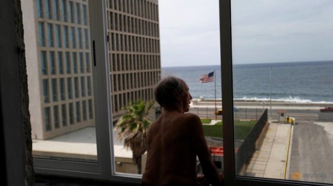 Một người đàn ông nhìn qua Đại sứ quán Mỹ tại Havana từ cửa sổ căn hộ của mình - Ảnh: Reuters