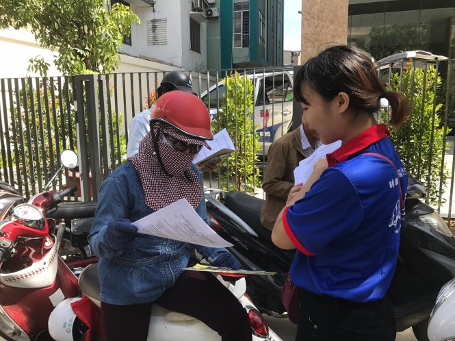 Một “tình nguyện viên” dỏm đi tiếp thị phát tờ rơi cho phụ huynh thí sinh - Ảnh: TRƯỜNG TRUNG