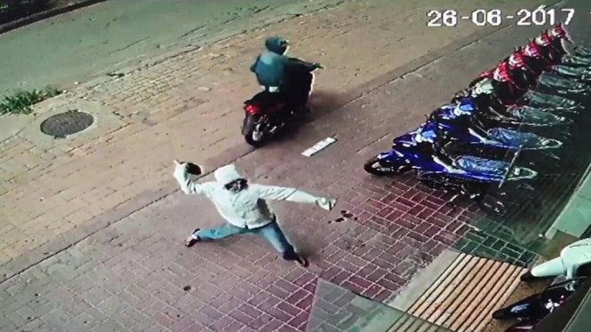 Hình ảnh nam thanh niên ném “bom bẩn” vào cửa hàng xe máy Huệ Lộc - Ảnh: H.LỘC