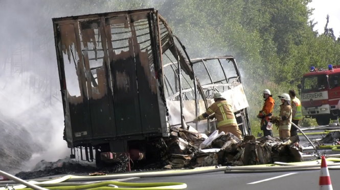Lính cứu hỏa tại hiện trường chiếc xe buýt cháy chỉ còn trơ khung sáng 3-7 - Ảnh: Reuters