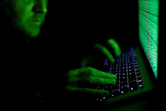 Một người đàn ông gõ mã mạng trước màn hình máy tính - Ảnh: Reuters