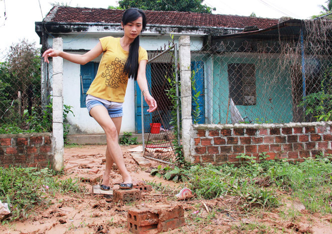 Sân đầy bùn muốn ra vào nhà, chị Phúc phải đợi trời tạnh và dùng gạch, gỗ, chiếu làm cầu - Ảnh: TRẦN MAI