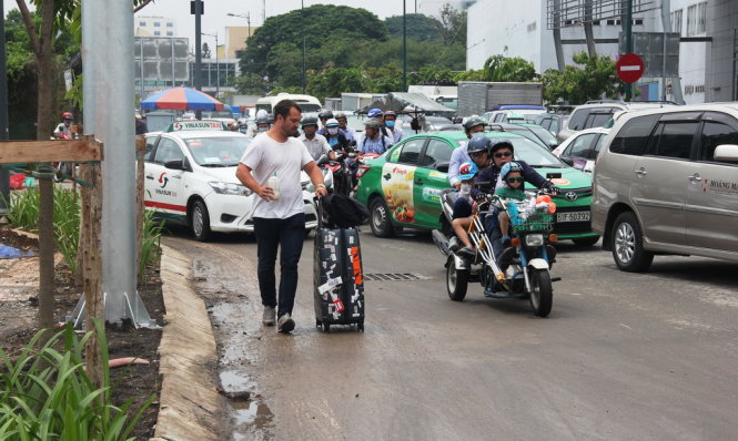 : Hành khách xuống xe, kéo hành lý đi bộ vào sân bay trên đường Bạch Đằng – Ảnh: HẢI HIẾU