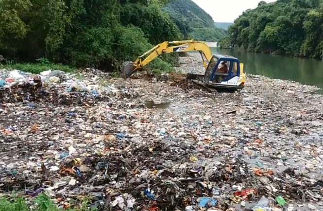 Chiếc máy xúc đang cào rác đổ xuống suối - Ảnh cắt từ clip