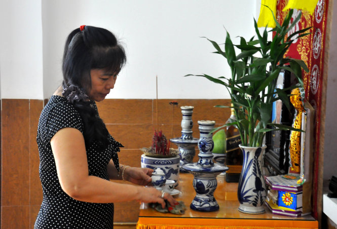 Bà Lê Thị Minh Thủy trước bàn thờ chồng và con