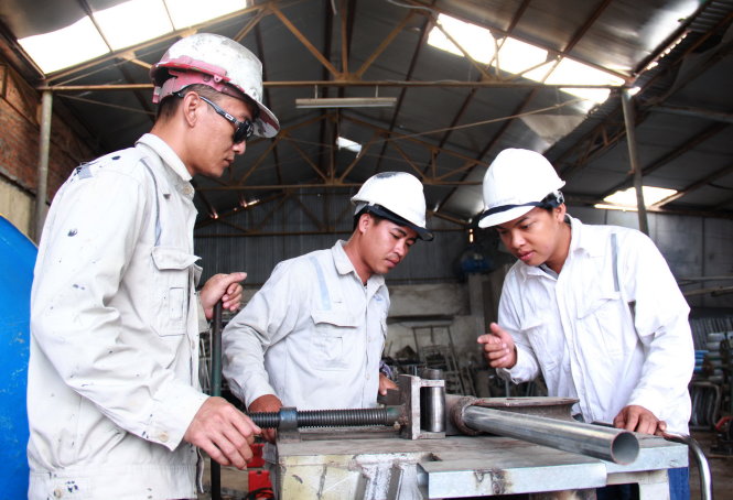 Đặng Duy Thạnh (bìa phải) cùng những cộng sự của mình cân đối lại từng chi tiết trong máy uốn nén kim loại trước khi đưa vào sản xuất đại trà - Ảnh: TRẦN MAI