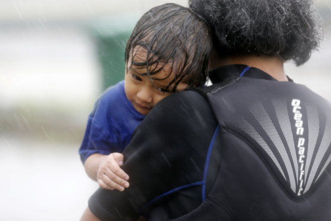 Em bé theo mẹ đi di tản dưới mưa ở TP Houston ngày 28-8 - Ảnh: REUTERS