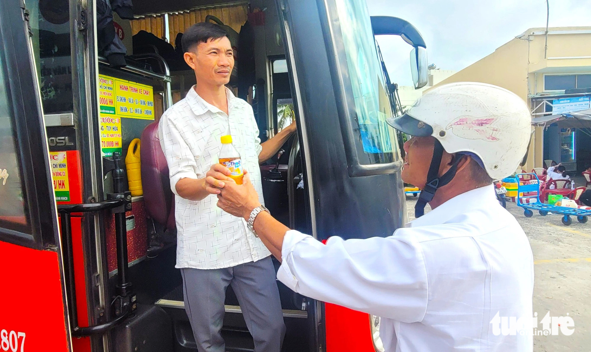 Ông Nguyễn Khoa Nam đưa chai nước cho con trai để uống trên đường xe chạy vào TP.HCM - Ảnh: NGUYỄN HOÀNG Ông Nguyễn Khoa Nam đưa chai nước cho con trai ở bến xe - Ảnh: NGUYỄN HOÀNG