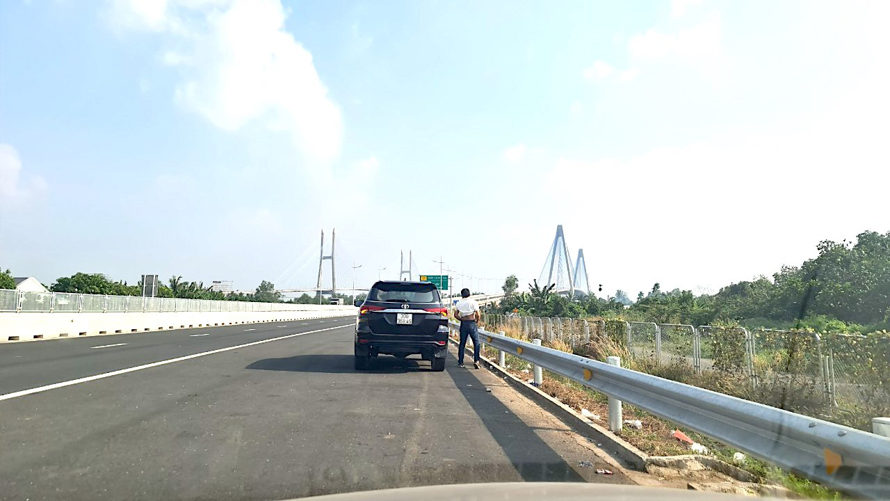 Cao tốc về miền Tây thiếu trạm dừng chân, tài xế dừng xe bất chấp- Ảnh 2. Một tài xế phải dừng xe bên đường cao tốc để tiểu tiện vì không có trạm dừng chân - Ảnh: MẬU TRƯỜNG