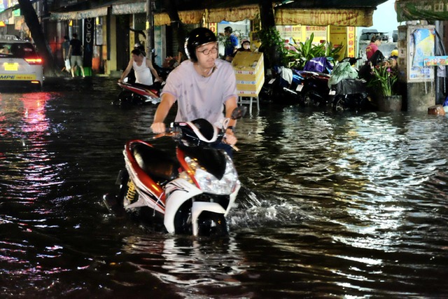 Heavy rain paralyzes Ho Chi Minh City traffic, forces commuters onto sidewalks- Ảnh 7. Heavy rain paralyzes Ho Chi Minh City traffic, forces commuters onto sidewalks- Ảnh 7.