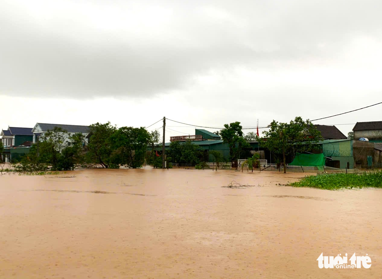 Mưa lớn và lũ đổ về khiến làng mạc bị cô lập, đường sá chìm trong biển nước - Ảnh 1.