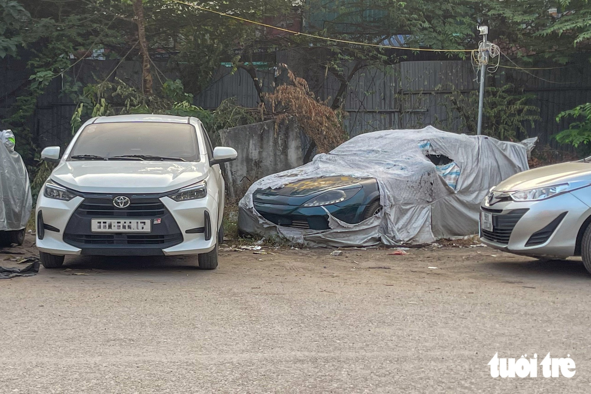 Một chiếc ô tô để trong thời gian dài, bạt che đã có dấu hiệu rách do ảnh hưởng từ thời tiết - Ảnh: PHÚC TÀIMột chiếc ô tô để trong thời gian dài, bạt che đã có dấu hiệu rách do ảnh hưởng từ thời tiết - Ảnh: PHÚC TÀI