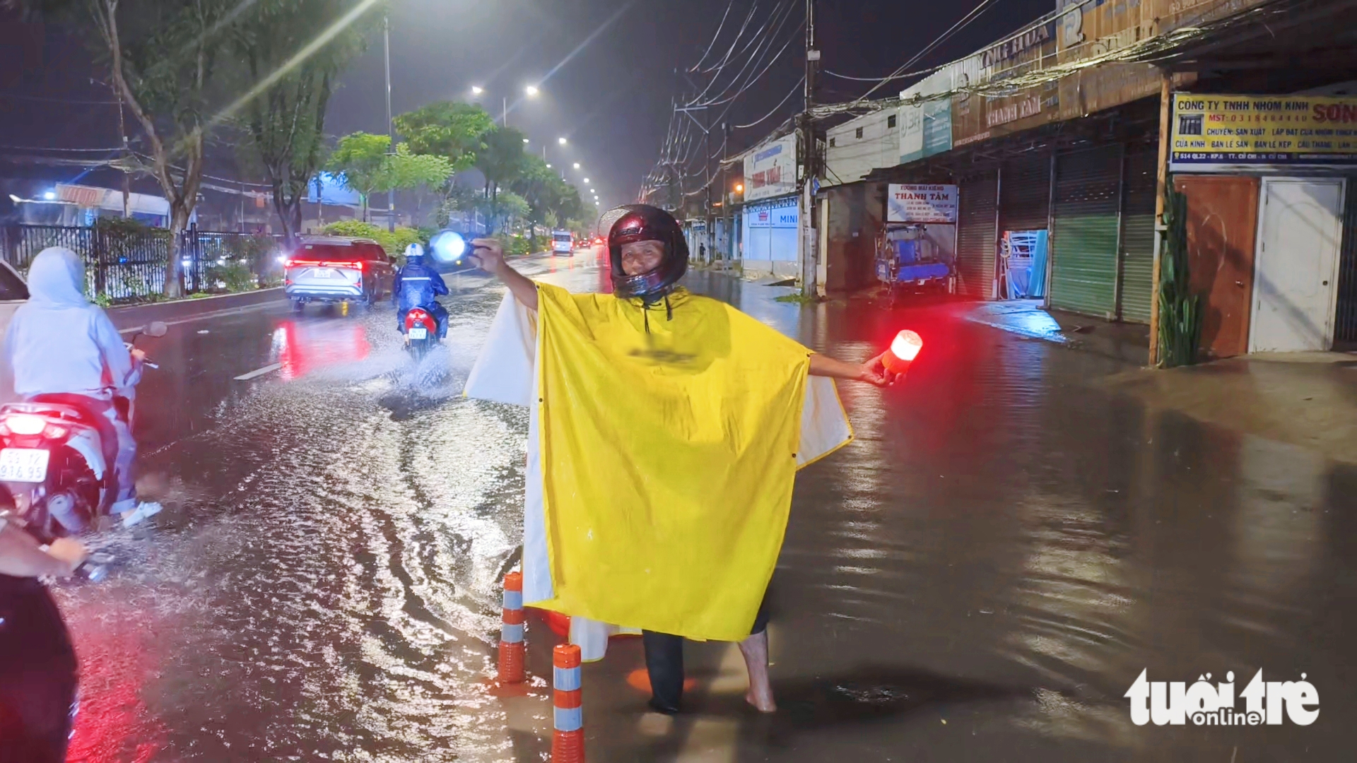 Người đàn ông ở Tân An Hội bì bõm trong đêm hướng dẫn xe tránh đoạn đường ngập - Ảnh 1.