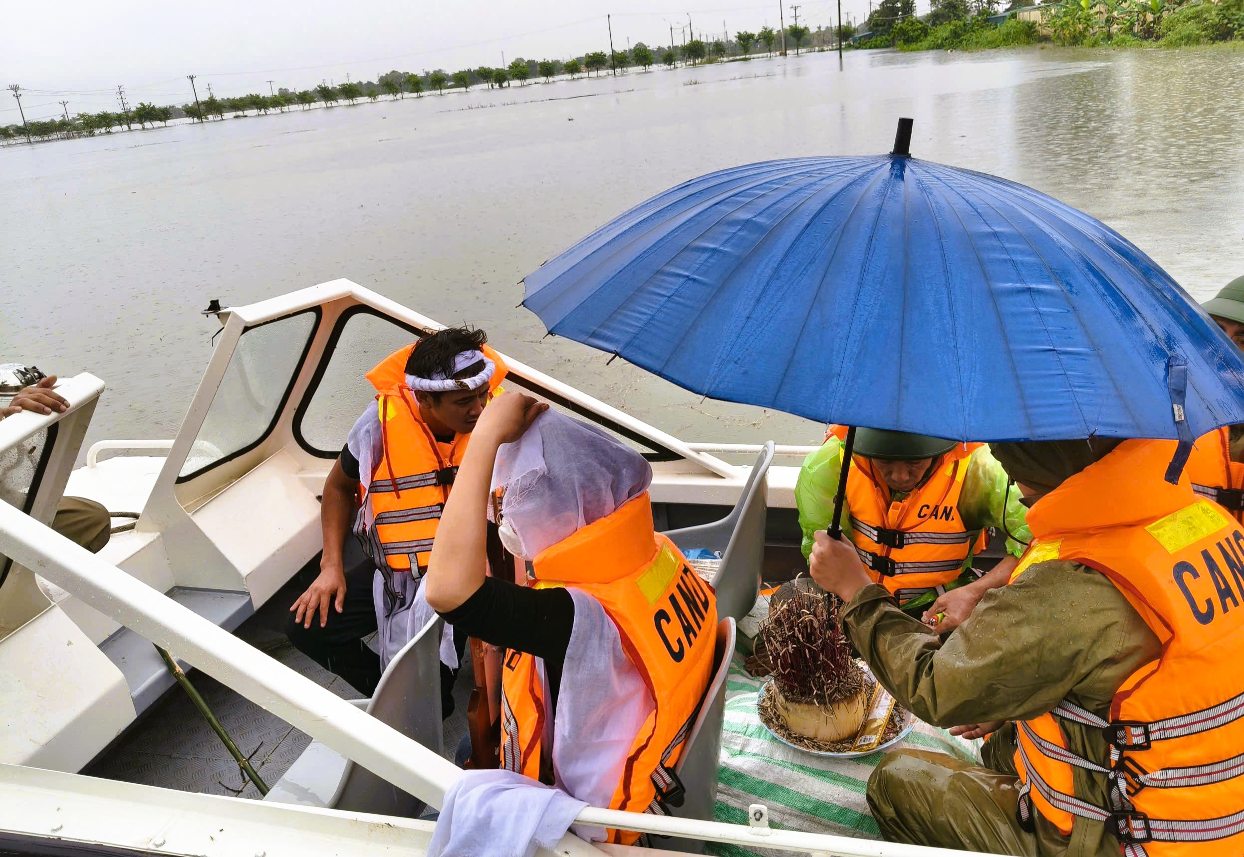 Cảnh sát dùng xuồng máy vượt nước lũ hỗ trợ đưa tro cốt về nhà tổ chức tang lễ - Ảnh 1.