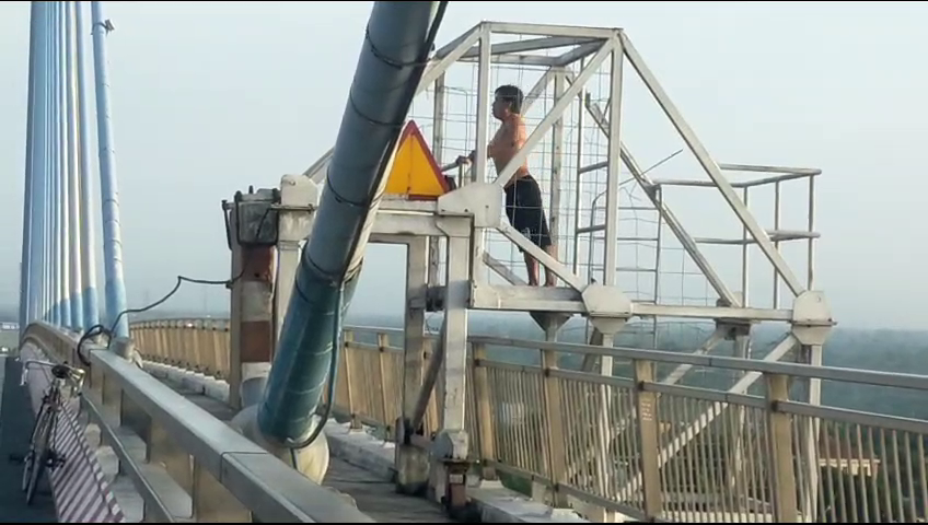 Người đàn ông leo lên lan can cầu Mỹ Thuận 1 tập thể dục, tiềm ẩn nguy hiểm - Ảnh 1.