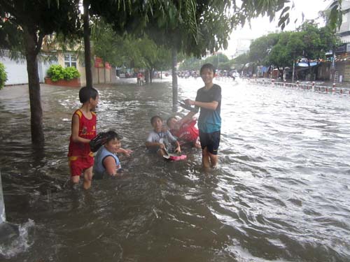 Trẻ em v&ocirc; tư vui đ&ugrave;a trong d&ograve;ng nước đen.