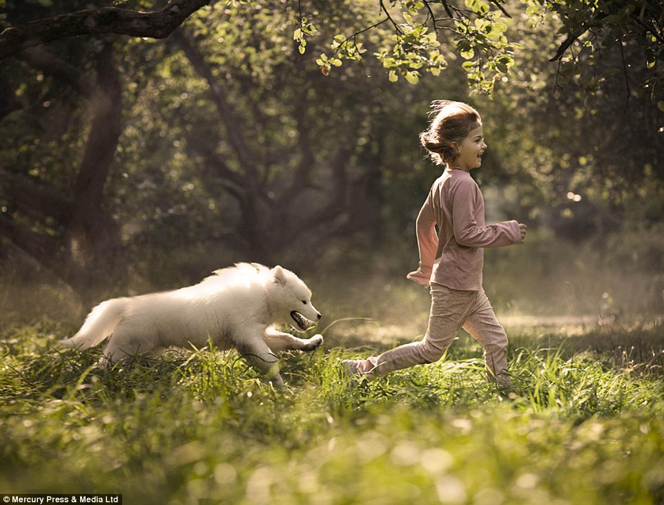 A young girl is chased by her dog as she charges through a woodland - the photographer said pets are members of our family&nbsp;