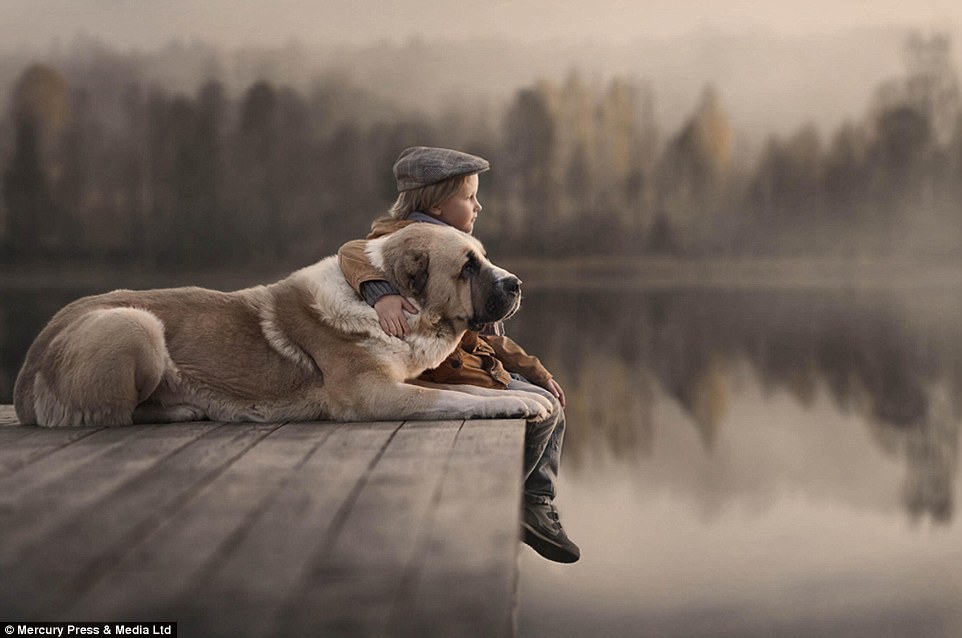 Photographer Elena Shumilova captures a young boy gazing out on to a lake with his arm wrapped around his pet dog&nbsp;