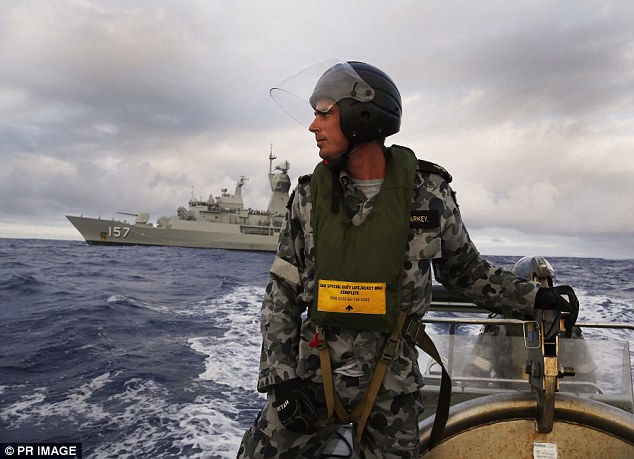 Leading Seaman, Boatswains Mate, William Sharkey searches for debris on a rigid hull inflatable boat in the Southern Indian Ocean in April. In the background is HMAS Perth, which was involved in the search