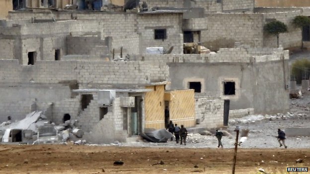 Unidentified armed men run through the Syrian town of Kobane (15 October 2014)