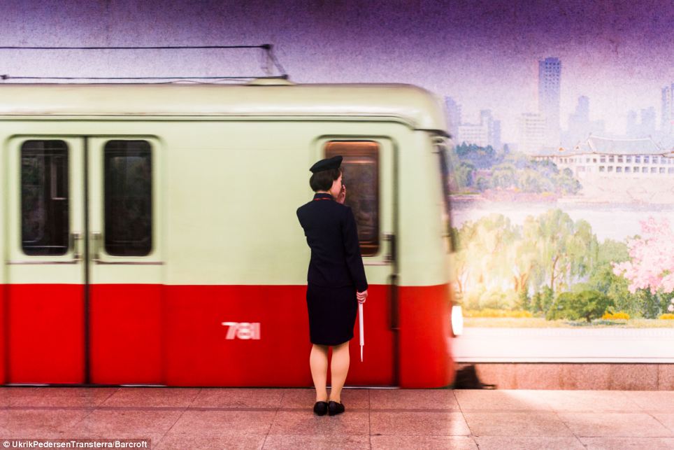 On the move: A female train guard waits for a train on North Koreas metro system in front of a mural painted on the far wall