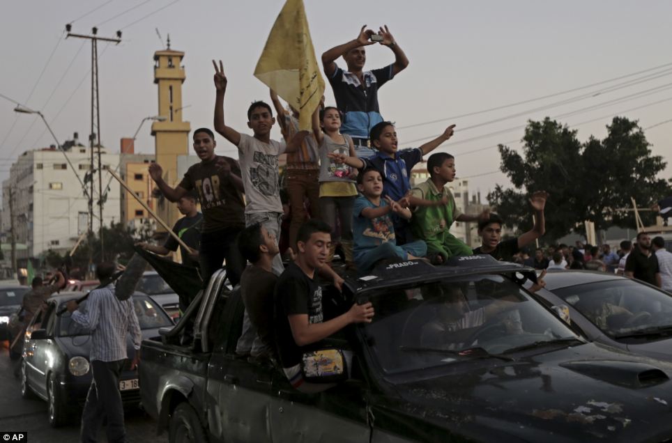 Joyful: Palestinians celebrate the cease-fire by riding down the main road in Gaza. The conflict killed more than 2,200 people, the vast majority of them Palestinians