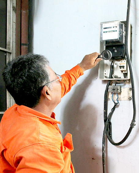 Nh&acirc;n vi&ecirc;n điện lực đang kiểm tra đồng hồ điện tại một nh&agrave; d&acirc;n.