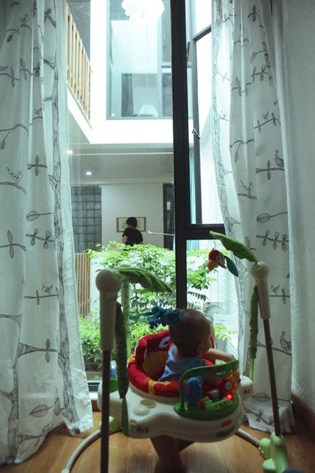 Nhờ c&oacute; giếng trời v&agrave; cửa k&iacute;nh, từ ph&ograve;ng kh&aacute;ch, bố mẹ vẫn c&oacute; thể dễ d&agrave;ng quan s&aacute;t cậu con trai nhỏ đang chơi trong ph&ograve;ng.