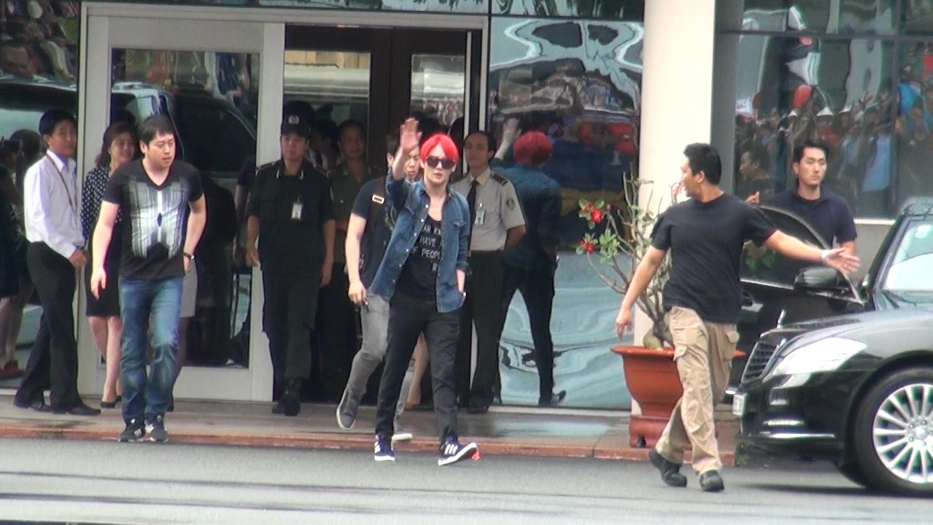 Kim Junsu (t&oacute;c đỏ) vẫy tay ch&agrave;o c&aacute;c fan Việt Nam khi ra khỏi cổng VIP s&acirc;n bay T&acirc;n Sơn Nhất. Ảnh: Quốc Thắng