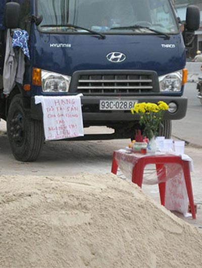 Viết yêu cầu đòi nợ treo trước xe tải (ảnh lớn) và trên áo (ảnh nhỏ) Ảnh: Như Phú