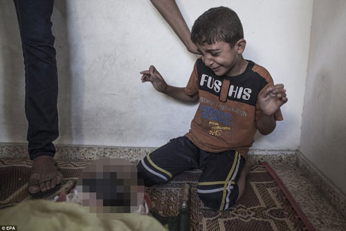 Cậu bé người Palestine trào nước mắt khi nhìn thấy thi thể người thân thiệt mạng trong vụ tấn công của Israel vào trường học của Liên Hiệp Quốc Ảnh: EPA